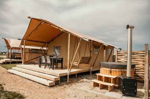 Alloggio glamping presso Strandpark De Zeeuwse Kust - Safaritenten Zeeland, con terrazza e vasca calda.