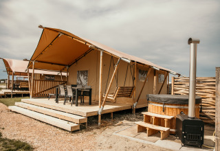 Glampingaccommodatie bij Strandpark De Zeeuwse Kust - Safaritenten Zeeland met veranda en hottub.