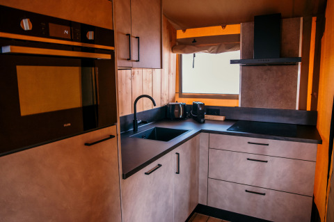 Angolo cottura moderno in una tenda safari glamping a Strandpark De Zeeuwse Kust, con forno e lavello.