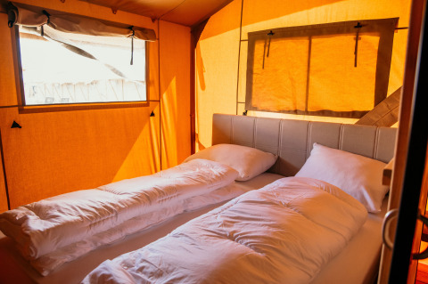 Interieur van een comfortabele safaritent op Strandpark De Zeeuwse Kust met luxe bedden en warme sfeer.
