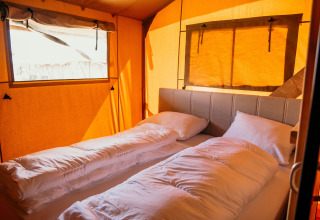 Indvendig udsigt af en komfortabel glamping-telt på Strandpark De Zeeuwse Kust med bløde senge.