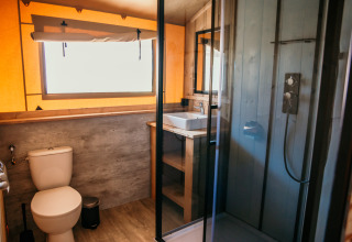 Moderne badeværelse med toilet, bruser og håndvask i glamping safari telt på Strandpark De Zeeuwse Kust.