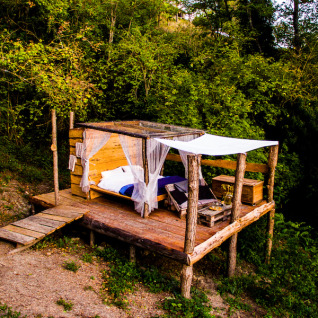 Buiten glamping accommodatie bij Novanta Skylodge in Italië, houten vlonder te midden van de natuur.