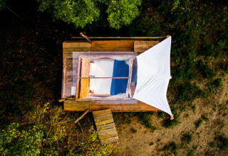 Vue aérienne du Novanta Skylodge en Italie, glamping avec lit et toile sur une plateforme en bois dans la nature.