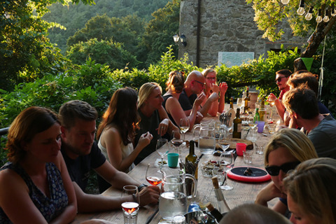 Group dining at a long outdoor table surrounded by nature at Novanta Skylodge - Italy, glamping ambiance.