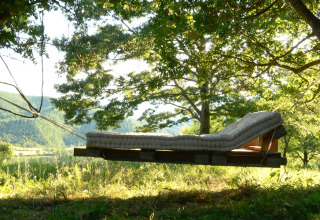 En hævet sengeskammel med madras hængende i træer, Novanta Skylodge - Italien, glamping oplevelse.