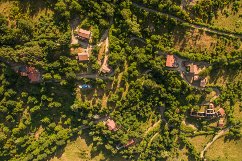 Aerial view of Novanta Skylodge in Italy, glamping accommodation nestled among trees and winding paths.