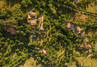 Luchtfoto van Novanta Skylodge in Italië, glamping accommodatie tussen bossen en kronkelende paadjes.