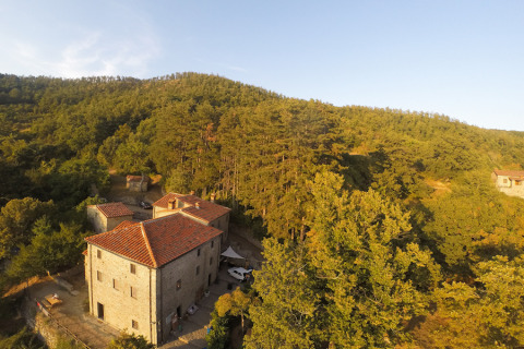 Alojamiento glamping en Novanta Skylodge, Italia, rodeado de colinas boscosas y vegetación bajo luz cálida.