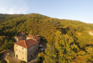 Hébergement glamping Novanta Skylodge en Italie, entouré de collines boisées sous la lumière du soir.