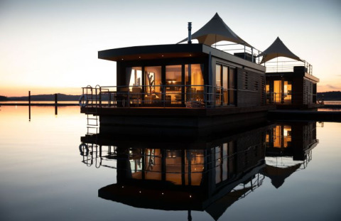 Drijvende lodge bij valavond in Floating Village Brombachsee, luxe glampingverblijf in Beieren, Duitsland.