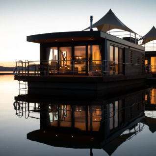 Floating lodge during sunset at Floating Village Brombachsee, modern glamping accommodation in Bavaria, Germany.