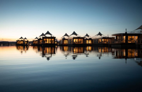 Floating Village Brombachsee-Lodges in Beieren bij avondlicht, sfeervol weerspiegeld in het water.