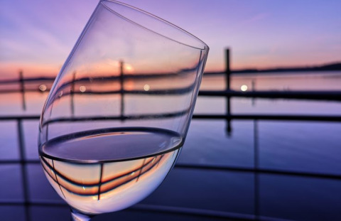 Verre de vin devant un coucher de soleil sur un lac paisible à Floating Village Brombachsee - Lodges Bayern.