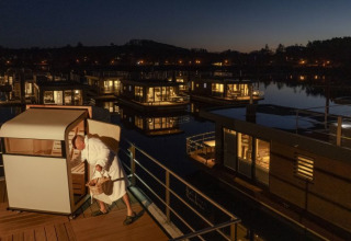 Floating Village Brombachsee : lodges sur l’eau de nuit, personne en peignoir près d’un sauna extérieur.
