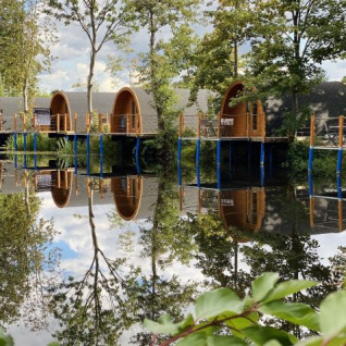 Lakeside glamping at Campotel Nord-Ostsee - Pods Schleswig-Holstein, nestled among scenic green trees.