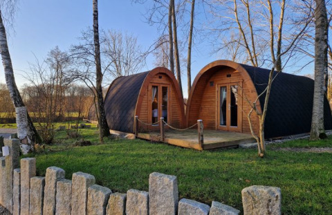Campotel Nord-Ostsee - Pods Schleswig-Holstein: alloggi glamping moderni immersi nel verde tra alberi e prato.