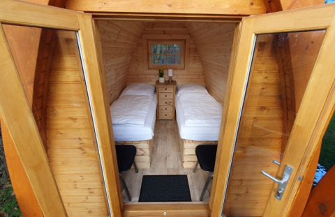 Interior view of a wooden camping pod with twin beds and nightstand at Campotel Nord-Ostsee, Schleswig-Holstein.