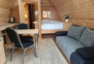 Vista interna di un pod in legno al Campotel Nord-Ostsee in Schleswig-Holstein con divano e letto.