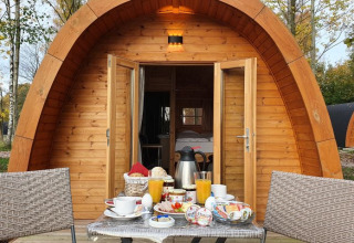 Campotel Nord-Ostsee Pods in Schleswig-Holstein mit gedecktem Frühstückstisch vor einem Holzpod.