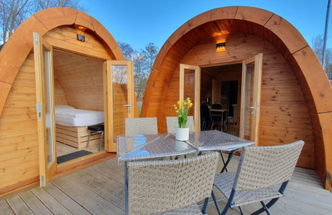 Gemütliche Glamping-Pods aus Holz mit Terrasse, Esstisch und Stühlen bei Campotel Nord-Ostsee, Schleswig-Holstein.