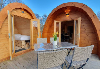 Gemütliche Glamping-Pods aus Holz mit Terrasse, Esstisch und Stühlen bei Campotel Nord-Ostsee, Schleswig-Holstein.