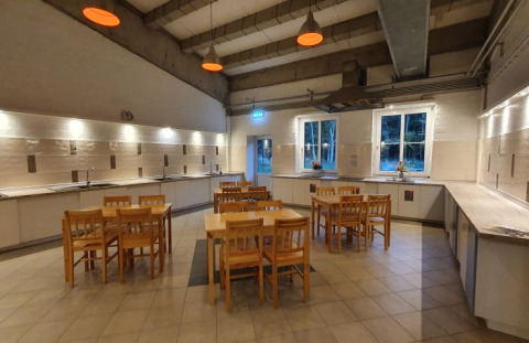 Cuisine commune spacieuse du Campotel Nord-Ostsee - Pods Schleswig-Holstein avec mobilier en bois et grandes fenêtres.