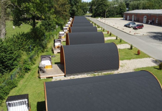 Fila de glamping pods en Campotel Nord-Ostsee, Schleswig-Holstein, con terrazas y zonas verdes alrededor.