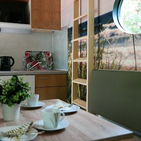 Alojamiento glamping moderno en tiny house en Baja Sajonia, cocina compacta y ventana redonda con vista.