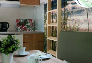 Moderne glamping tiny house in Nedersaksen met compacte keuken, eettafel en rond raam met uitzicht.