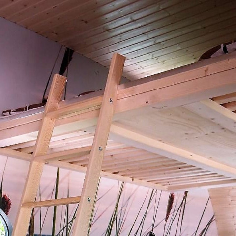 Intérieur d'une petite maison en bois avec mezzanine et échelle, glamping moderne en Basse-Saxe, Pays-Bas.