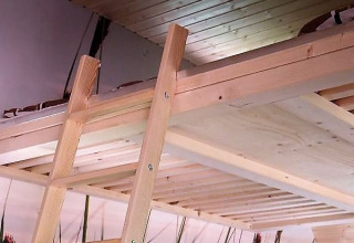 Innenraum eines kleinen Holzhauses mit Hochbett und Leiter, modernes Glamping in Niedersachsen.