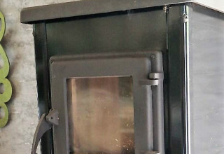 Schwarzer Holzofen mit Glastür in einer Glamping-Unterkunft bei Klein vakantie- en tentoonstellingspark, Tiny houses.