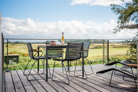 Terrasse extérieure des Lütetsburg Lodges - Boomhutten Nedersaksen avec table, chaises et vue sur la campagne.