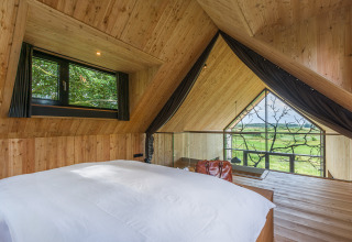 Vista interior de una lujosa cabaña en Lütetsburg Lodges - Boomhutten Nedersaksen con vistas al paisaje verde.