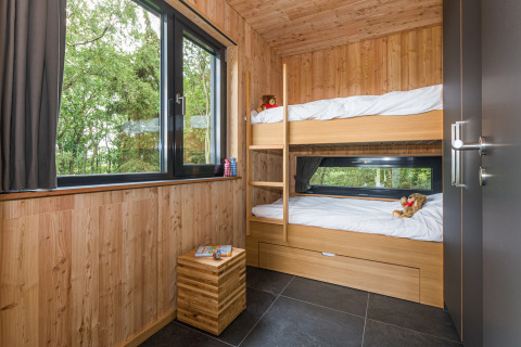 Hébergement glamping moderne avec lits superposés, grandes fenêtres et murs en bois aux Lütetsburg Lodges.