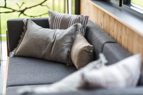 Sfeervolle glampingbank met kussens in Lütetsburg Lodges - Boomhutten Nedersaksen, bij het raam.