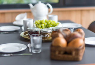 Breakfast setup at Lütetsburg Lodges - Boomhutten Nedersaksen with rolls, grapes, and assorted jams.