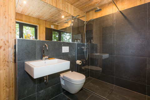 Salle de bain moderne en bois et carrelage noir aux Lütetsburg Lodges - Boomhutten Nedersaksen, glamping.