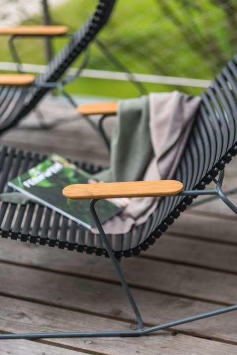 Chaise d'extérieur moderne avec accoudoirs en bois, couverture et magazine à Lütetsburg Lodges - Boomhutten Nedersaksen