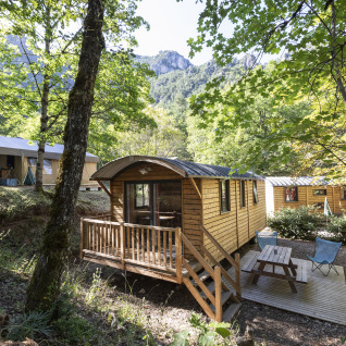 Wooden glamping cabins and tents under trees at Huttopia Gorges du Tarn - Glamping Midi-Pyrénées, France.
