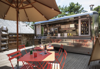 Zona de comedor al aire libre con food truck en Huttopia Gorges du Tarn Glamping en Midi-Pyrénées, Francia.