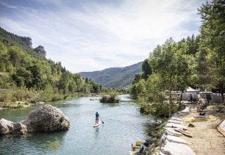 Persona su paddleboard in un fiume presso Huttopia Gorges du Tarn Glamping in Midi-Pyrénées, immerso nella natura.