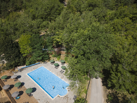 Aerial view of a pool and forest at Huttopia Gorges du Tarn - Glamping Midi-Pyrénées campsite in France.
