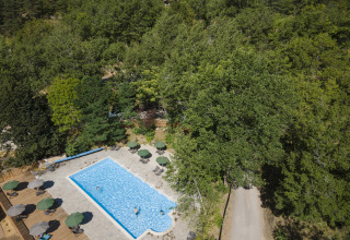 Vista aérea de una piscina y bosque en Huttopia Gorges du Tarn - Glamping Midi-Pyrénées, Francia.