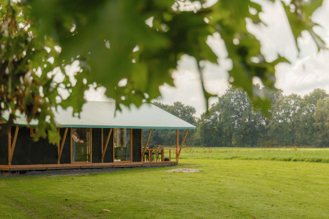 Glampingaccommodatie op Landrijk de Reesprong in de natuur, omringd door groene velden en bomen.