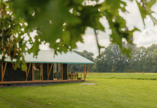 Glamping-indkvartering på Landrijk de Reesprong i naturen med grønne marker og træer i baggrunden.