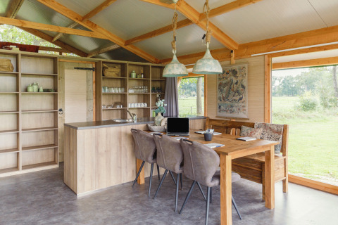 Modern glamping accommodation with open kitchen and dining table at Glamping - Landrijk de Reesprong.