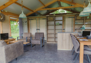 Interior of glamping accommodation Landrijk de Reesprong featuring cozy lounge and dining areas in wood.