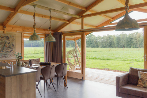 Interno di un alloggio glamping presso Landrijk de Reesprong con vista su prati verdi e paesaggio naturale.